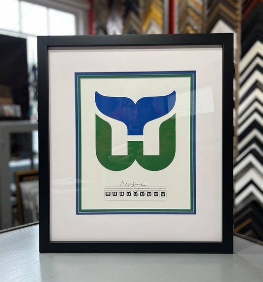Hartford Whalers logo print framed with white, blue, and green triple mats, black Confetti frame, and Conservation Clear Glass.