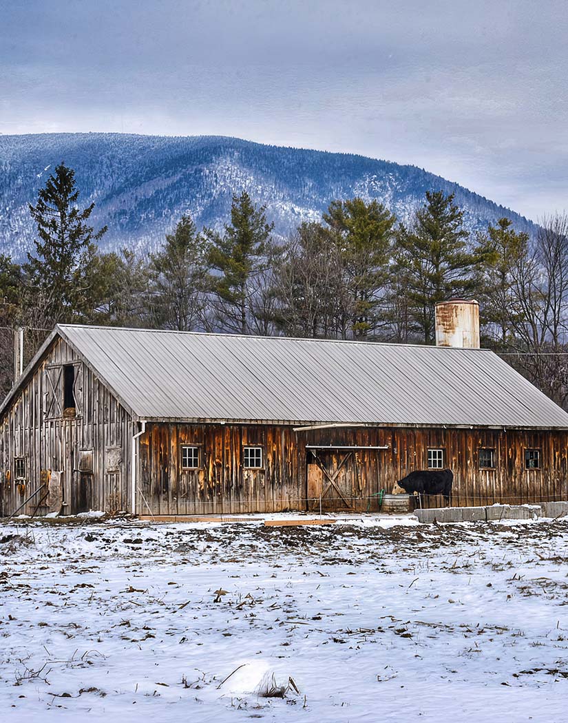 Wooden barn in a snowy landscape with mountains in the background
