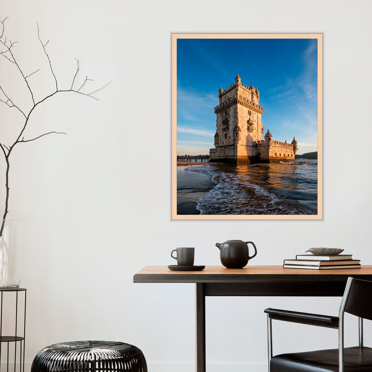 Framed photograph of a castle by the water on a wall above a table with decor items.
