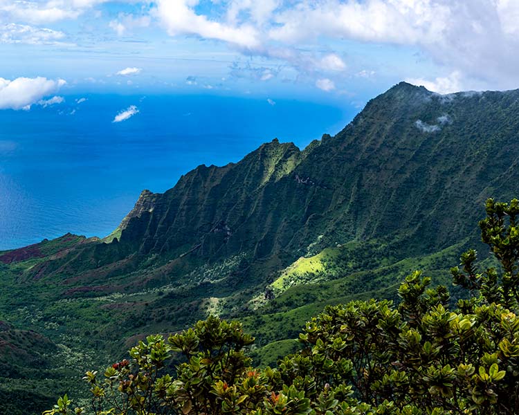 Scenic view of a mountain range with a clear blue sky and ocean.