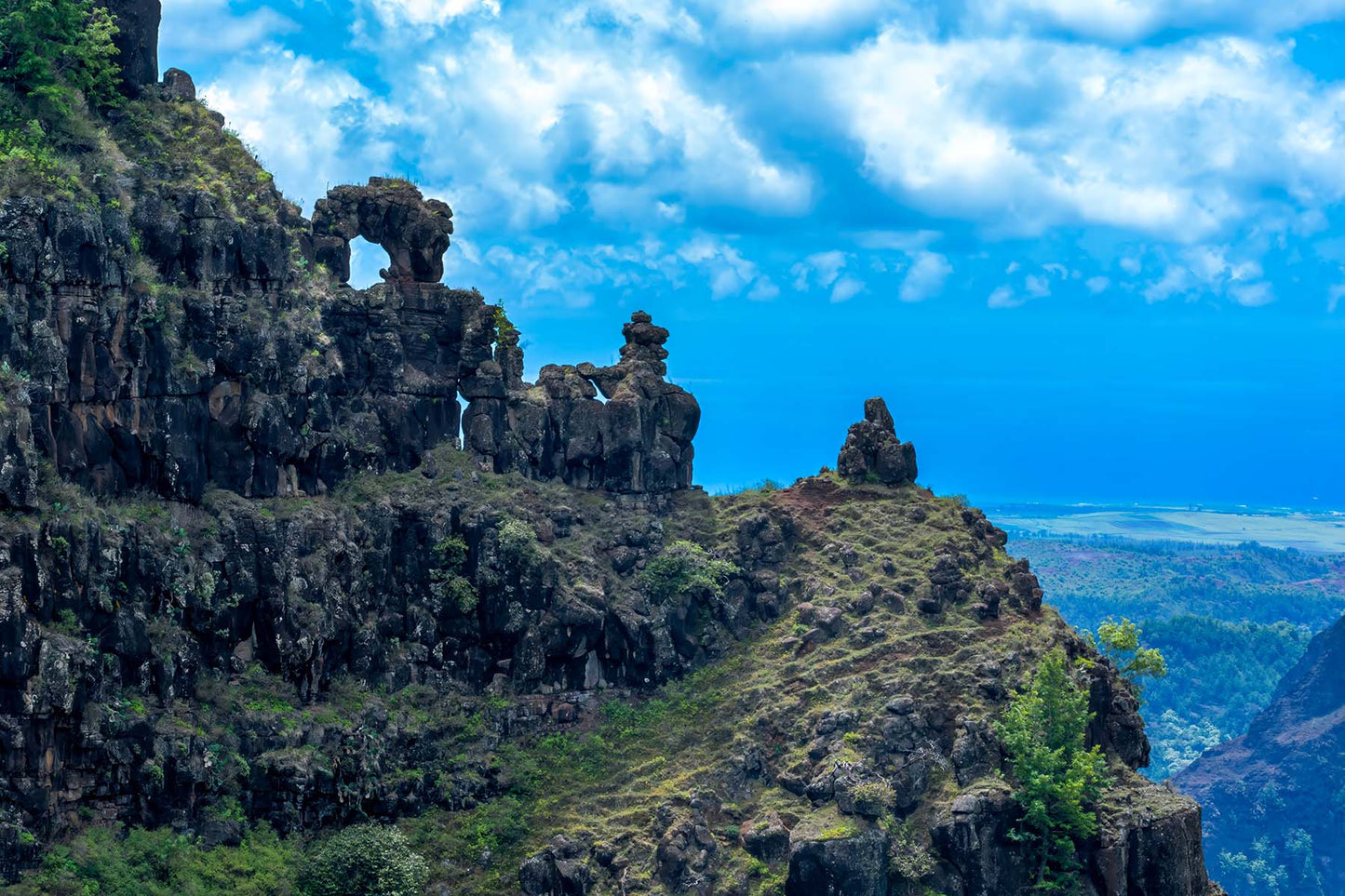 Rocks with a natural arch on a mountain cliff against a blue sky