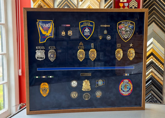 Shadowbox frame of police badges and medals in walnut frame on blue suede