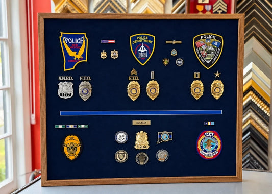 Shadowbox frame of police badges and medals in walnut frame on blue suede
