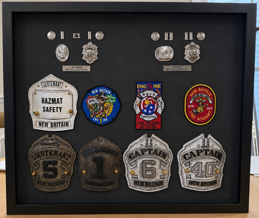 Firefighter career shadowbox with Lieutenant and Captain helmet shields, badges, patches, and insignia on a black background.