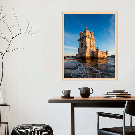 Framed photograph of a castle by the water on a wall above a table with decor items.