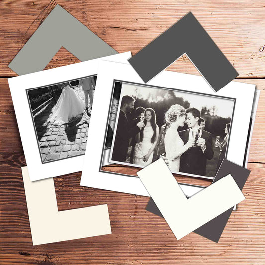 Set of photo frames and black and white photos on a wooden surface with matboard samples